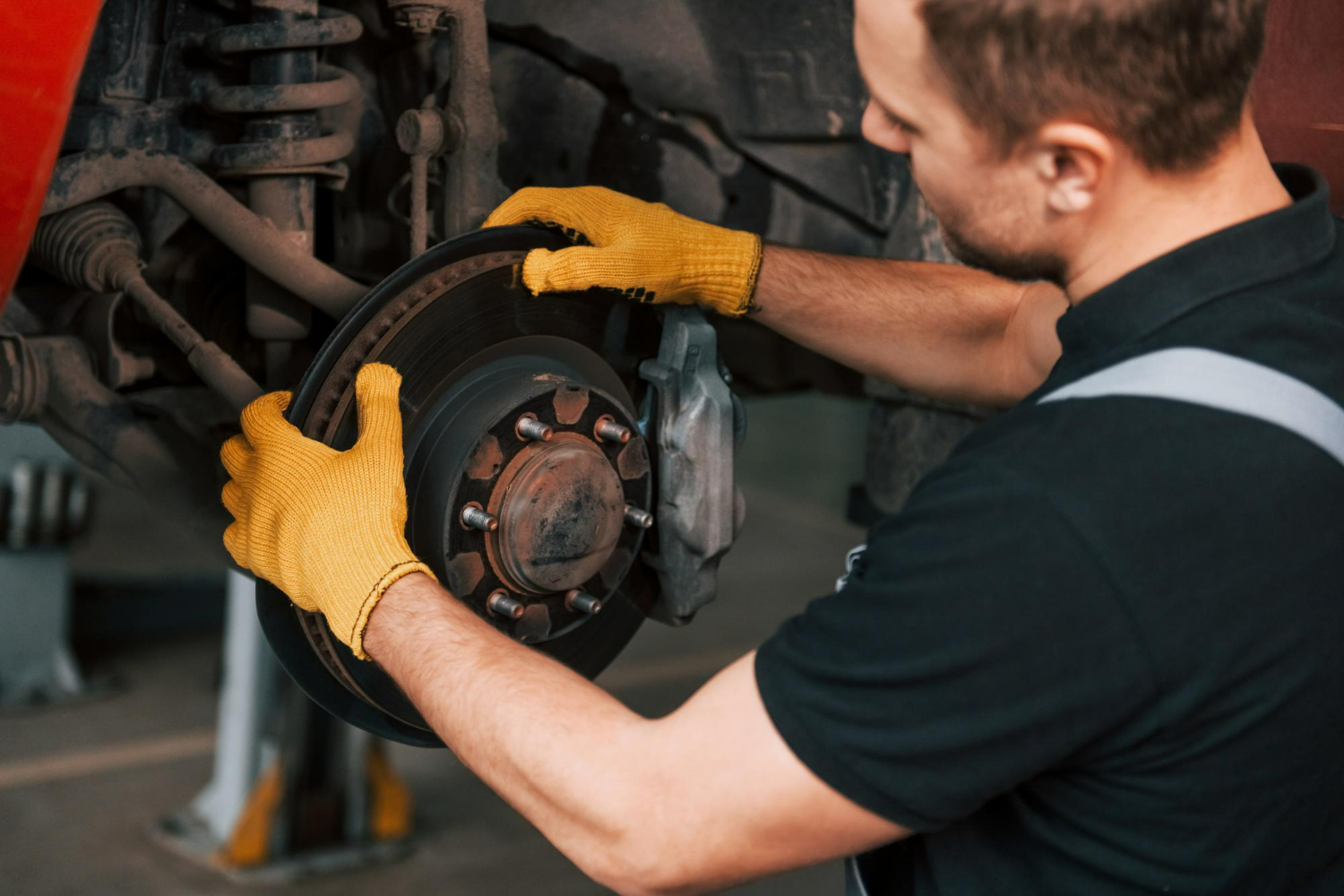 Mechanic inspecting and repairing car brake disc for optimal performance and safety.